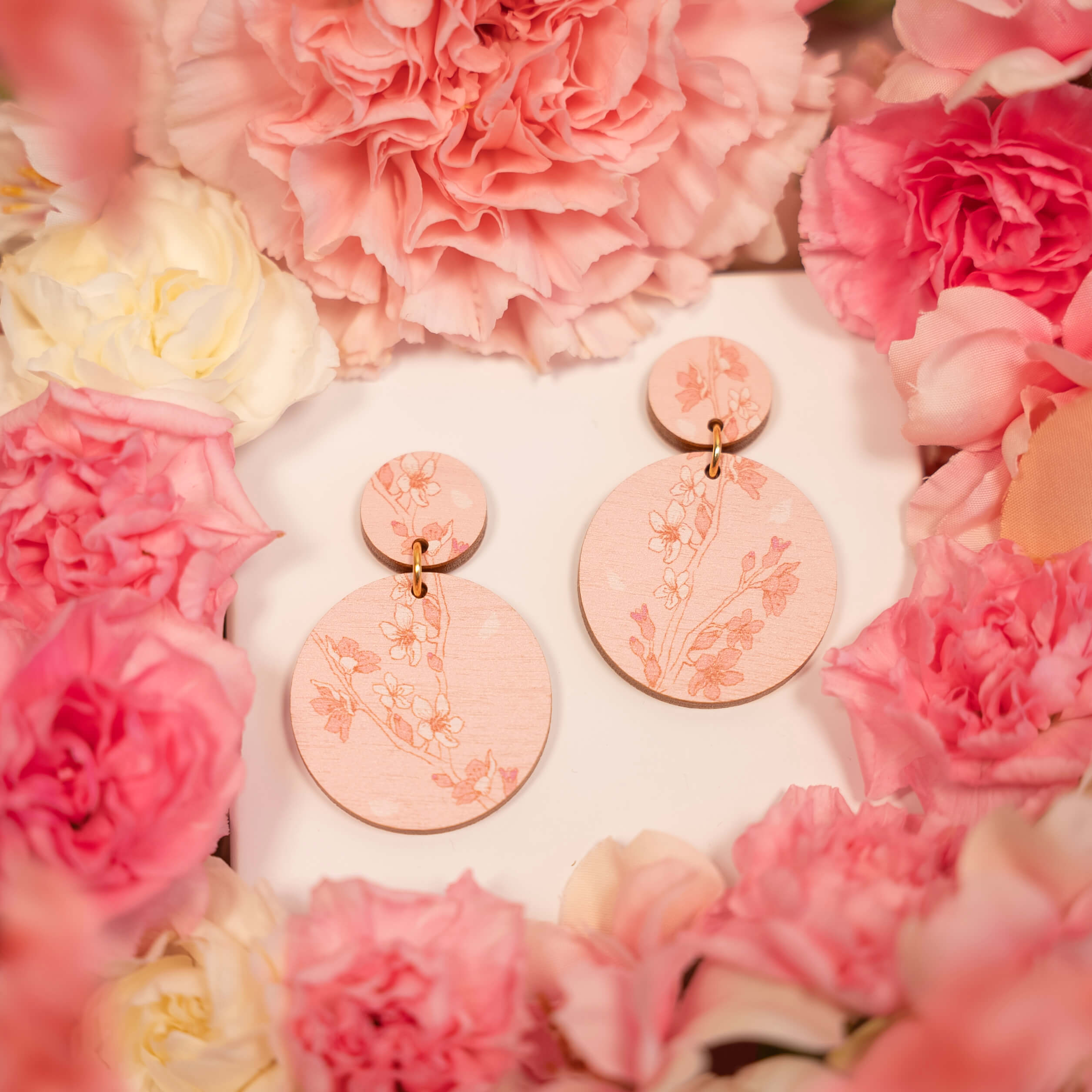 Sakura unelma -koru heijastaa vaaleanpunaisten unelmien ja kirsikankukkien suloista kauneutta. Lempeä vaaleanpunainen tausta ja herkät kukat kilpailevat keskenään hattaranpehmeistä unelmista, tehden tästä täydellisen vaaleanpunaisen korun. Sakura unelma -korvakoru on valmistettu Suomessa.